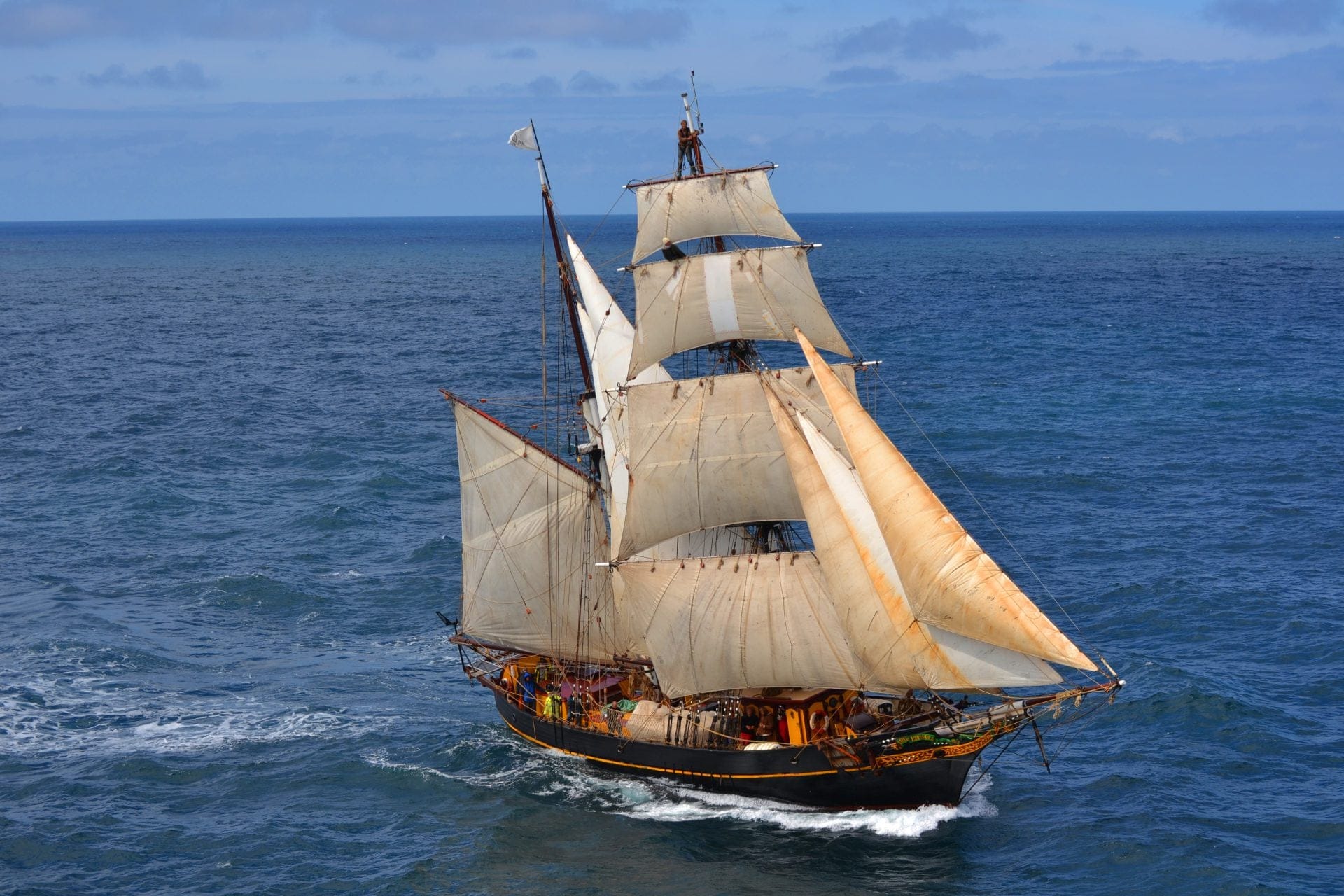Tres Hombres onder vol zeil op open zee, met bemanning in het want